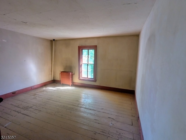 empty room featuring radiator and light hardwood / wood-style flooring