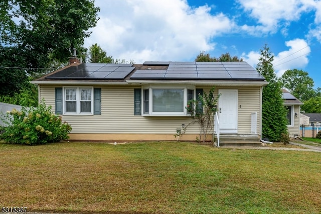 view of front of home with solar panels and a front lawn