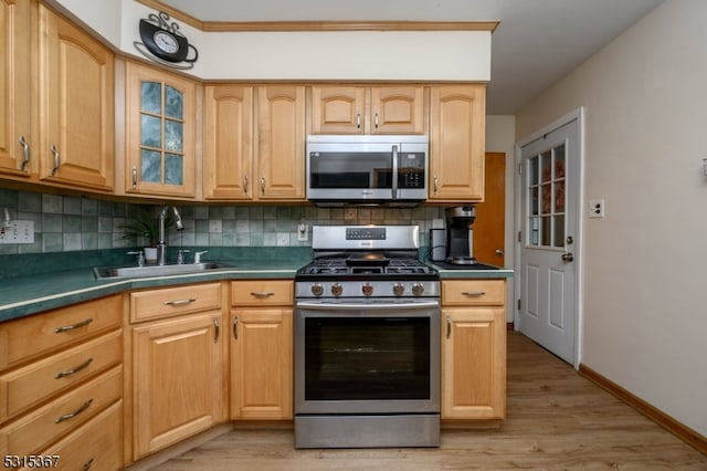 kitchen featuring appliances with stainless steel finishes, decorative backsplash, light wood-type flooring, and sink