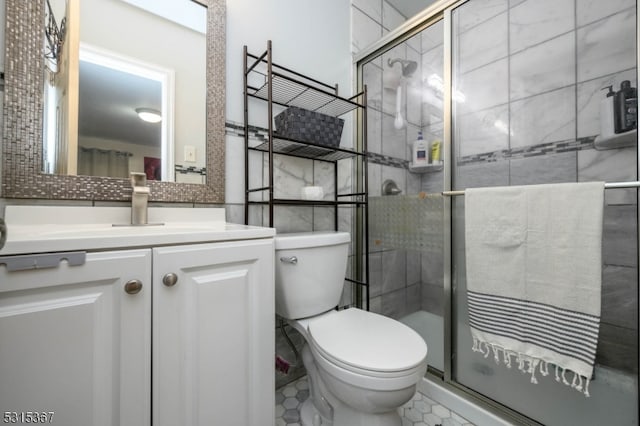 bathroom featuring walk in shower, vanity, toilet, and tile patterned floors