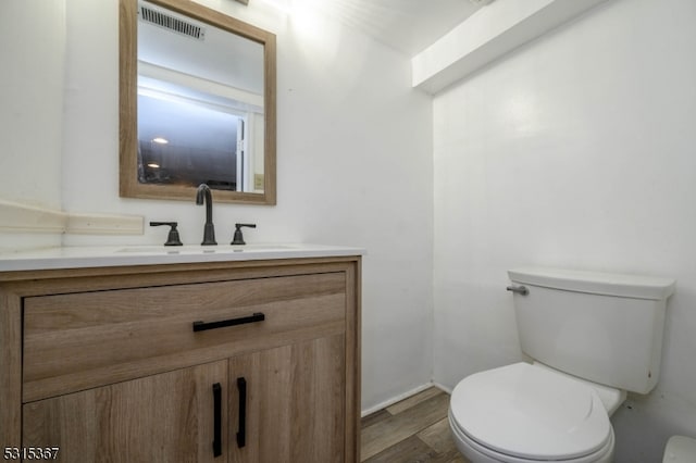 bathroom with wood-type flooring, vanity, and toilet