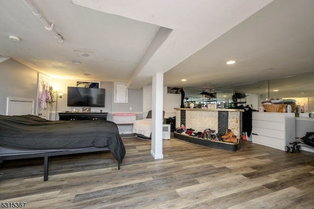 bedroom with hardwood / wood-style flooring, bar, and track lighting