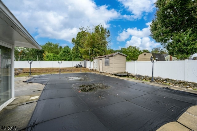 view of swimming pool with a storage unit and a patio area