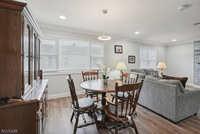 dining room with light wood-type flooring, crown molding, and a wealth of natural light