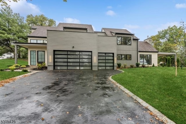 contemporary house featuring a garage, a chimney, board and batten siding, a front lawn, and driveway