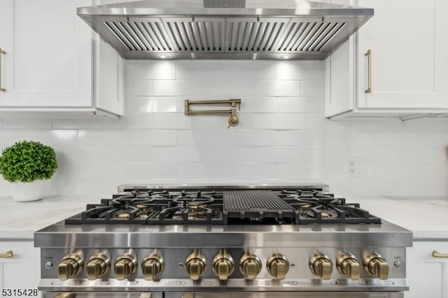 interior space with wall chimney exhaust hood, white cabinetry, stainless steel range, and light stone countertops