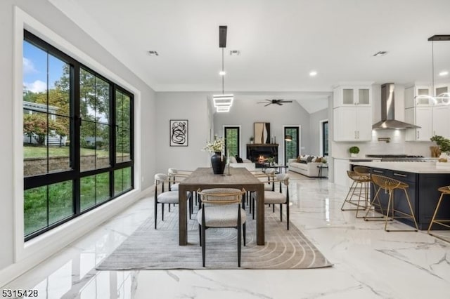 dining area with a ceiling fan, marble finish floor, recessed lighting, and a lit fireplace