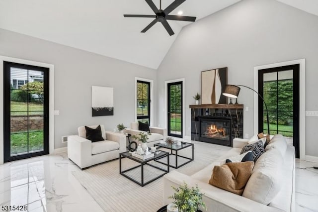 living area featuring baseboards, a tiled fireplace, ceiling fan, high vaulted ceiling, and marble finish floor