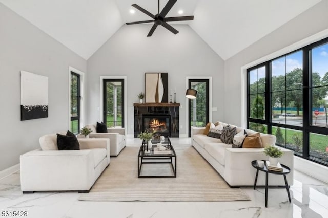 living area with high vaulted ceiling, ceiling fan, a glass covered fireplace, recessed lighting, and marble finish floor