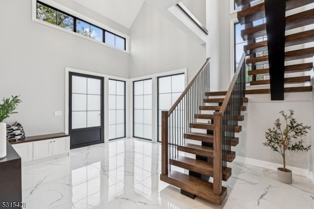 entryway featuring baseboards, stairway, marble finish floor, and a towering ceiling