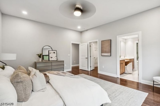 bedroom featuring baseboards, recessed lighting, ensuite bath, and wood finished floors
