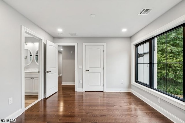unfurnished bedroom featuring dark wood-type flooring, ensuite bath, visible vents, recessed lighting, and baseboards