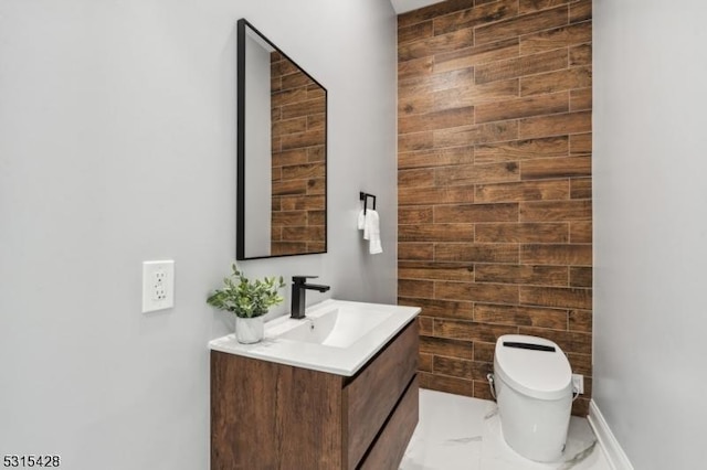 half bathroom featuring vanity, marble finish floor, and toilet