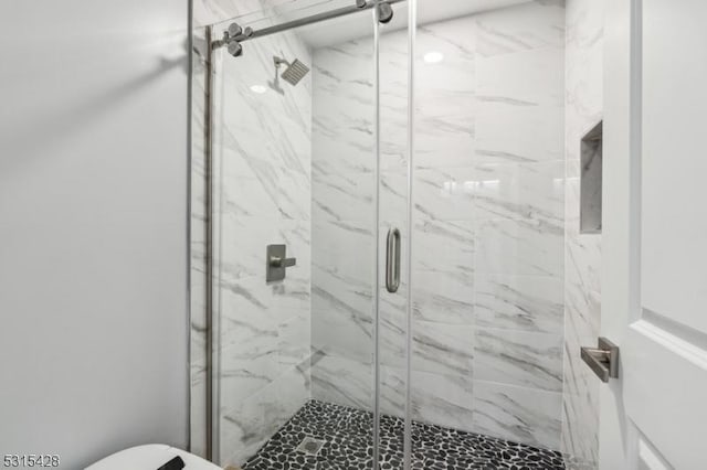 bathroom featuring a marble finish shower and toilet