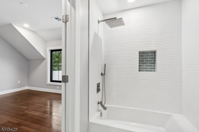 bathroom with tiled shower / bath combo and hardwood / wood-style floors