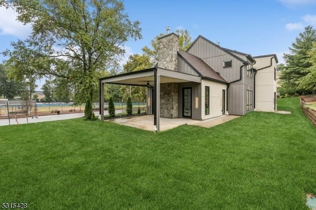 back of property with a chimney, a patio area, fence, and a lawn