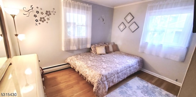 bedroom with hardwood / wood-style flooring, crown molding, and baseboard heating