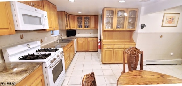 kitchen with light tile patterned flooring, sink, white appliances, baseboard heating, and light stone countertops