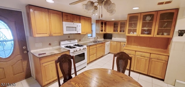 kitchen featuring light tile patterned flooring, white appliances, sink, and ceiling fan