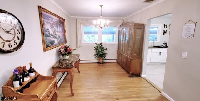 hall with a notable chandelier, light hardwood / wood-style floors, ornamental molding, and sink