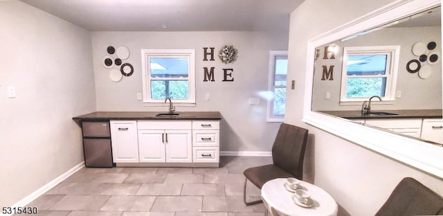 interior space featuring sink, light tile patterned floors, and white cabinets