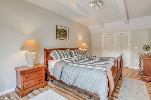 bedroom featuring light hardwood / wood-style flooring, vaulted ceiling with beams, and a closet