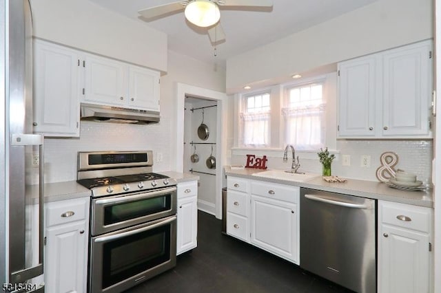 kitchen with under cabinet range hood, a sink, white cabinets, light countertops, and appliances with stainless steel finishes