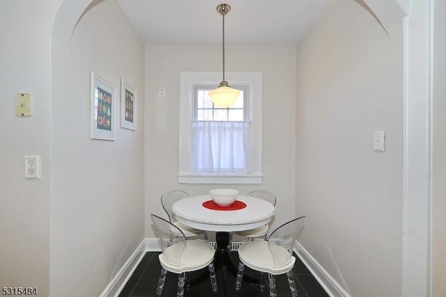 dining area featuring baseboards and arched walkways