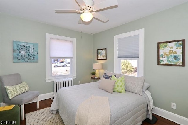 bedroom featuring radiator heating unit, multiple windows, baseboards, and wood finished floors