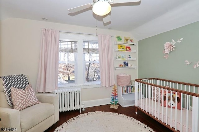 bedroom featuring lofted ceiling, dark wood-style flooring, baseboards, a nursery area, and radiator heating unit