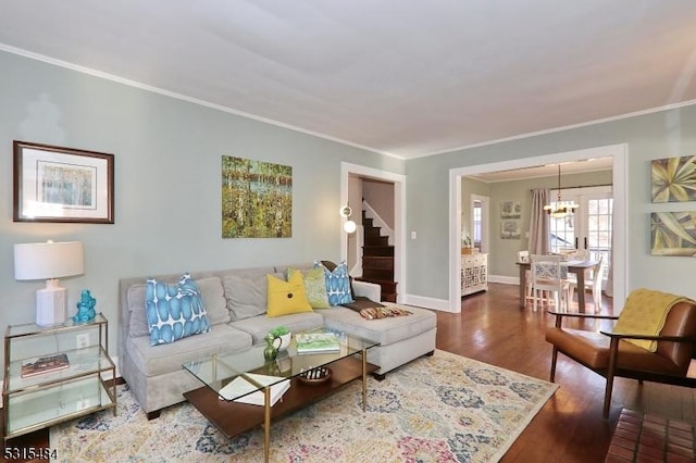 living room featuring crown molding, stairway, wood finished floors, a chandelier, and baseboards