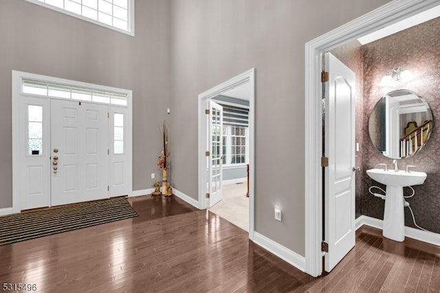 entryway with a towering ceiling and dark wood-type flooring