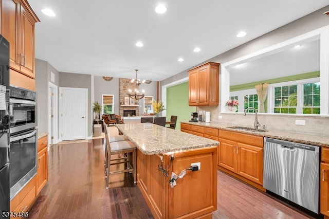 kitchen with hardwood / wood-style flooring, a chandelier, stainless steel appliances, sink, and a center island