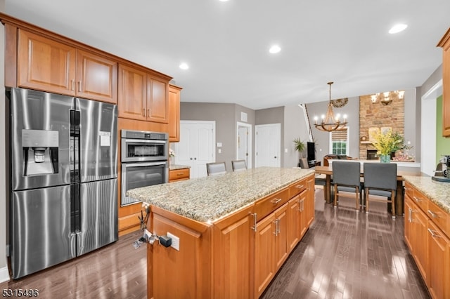 kitchen with a kitchen island, hanging light fixtures, an inviting chandelier, appliances with stainless steel finishes, and dark hardwood / wood-style flooring