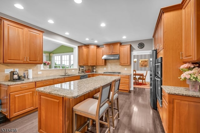 kitchen with a kitchen island, a kitchen breakfast bar, sink, vaulted ceiling, and dark hardwood / wood-style flooring