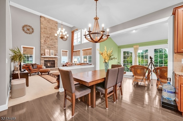 dining space featuring dark wood-type flooring, lofted ceiling with beams, a chandelier, and a fireplace