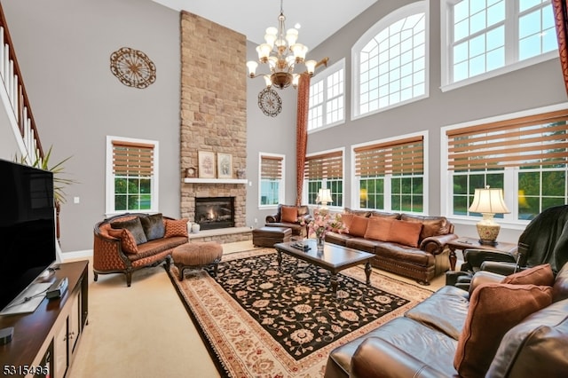 living room with a towering ceiling, light carpet, a stone fireplace, and an inviting chandelier