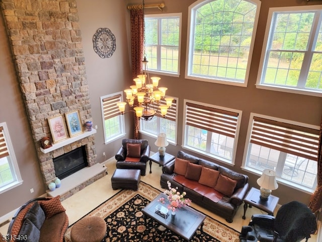 living room featuring a wealth of natural light, a notable chandelier, and a stone fireplace