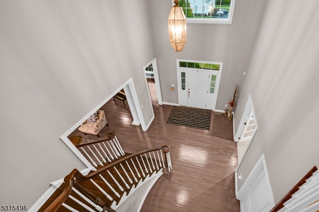 foyer featuring a towering ceiling, a chandelier, and hardwood / wood-style floors