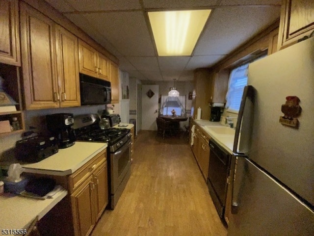 kitchen featuring light wood-type flooring, black appliances, and a paneled ceiling