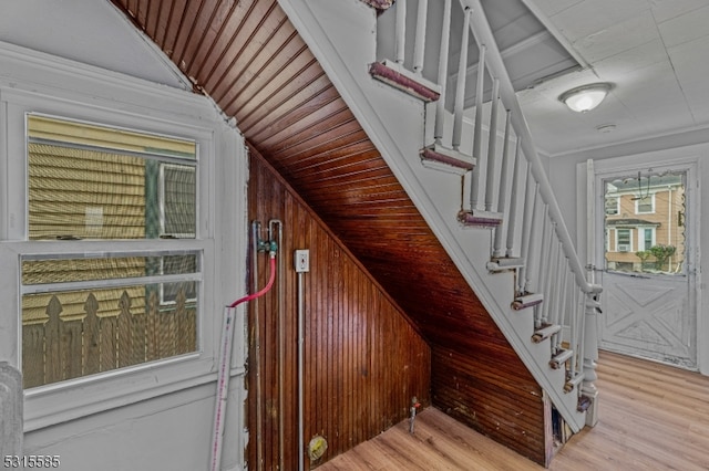 staircase featuring hardwood / wood-style flooring, wood walls, and vaulted ceiling