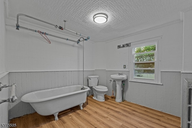 bathroom featuring a textured ceiling, wood-type flooring, toilet, a tub, and sink