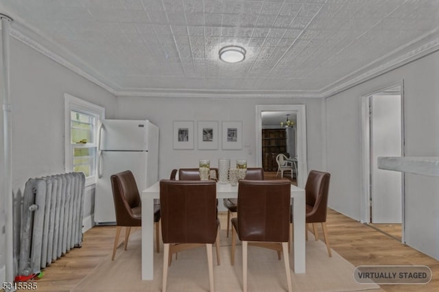 dining room featuring radiator heating unit, light hardwood / wood-style floors, and crown molding