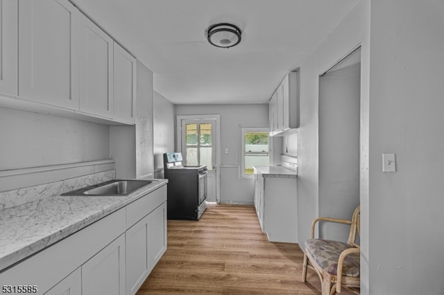 kitchen with white cabinetry, light stone countertops, light wood-type flooring, sink, and electric range