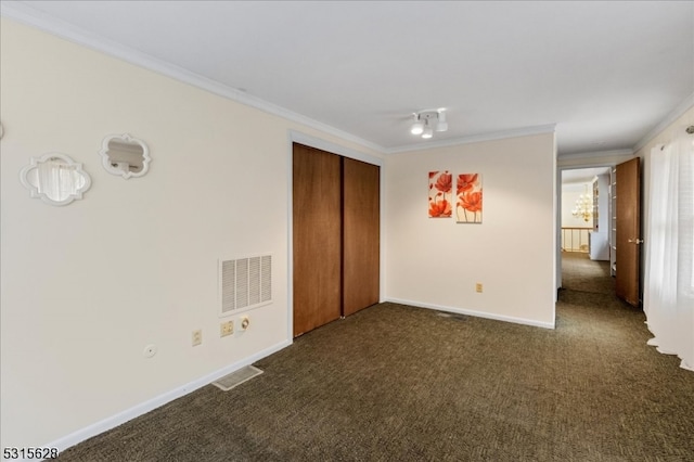 unfurnished bedroom with dark carpet, ornamental molding, and a closet