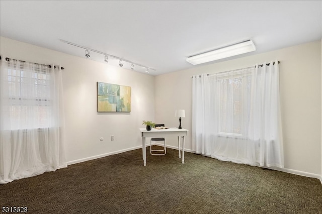 unfurnished office with dark carpet, rail lighting, and a wealth of natural light