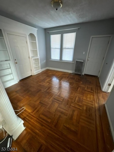 unfurnished bedroom featuring radiator and dark parquet flooring