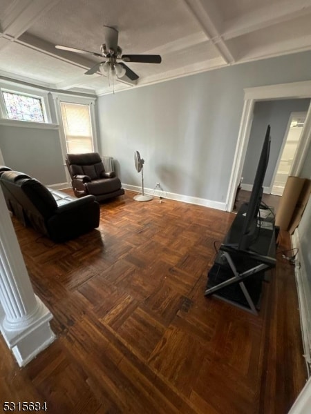 sitting room with dark parquet floors, ornamental molding, ceiling fan, and ornate columns