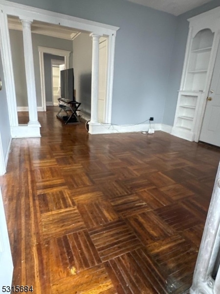 unfurnished room featuring ornamental molding, dark parquet floors, and decorative columns