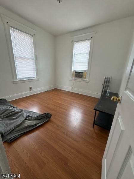 interior space featuring radiator heating unit, cooling unit, and hardwood / wood-style floors